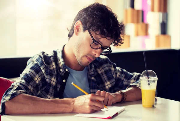 Homme avec cahier et jus écrit au café — Photo