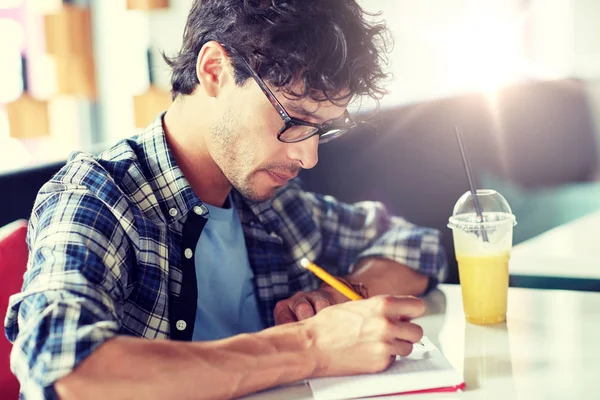 Homme avec cahier et jus écrit au café — Photo