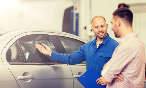 Automechaniker mit Klemmbrett und Mann im Autohaus — Stockfoto