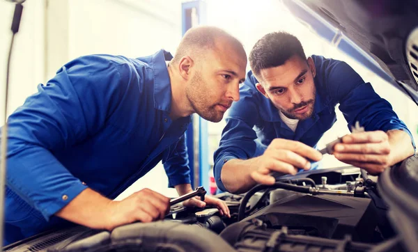 Hombres mecánicos con llave inglesa reparación de coches en el taller — Foto de Stock