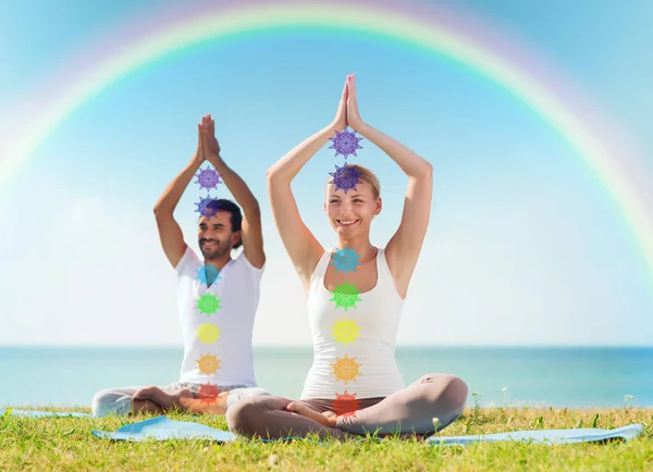 Coppia che fa yoga in posa loto con sette chakra — Foto Stock