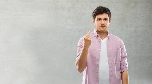 Man showing middle finger over grey concrete wall — Stock Photo, Image