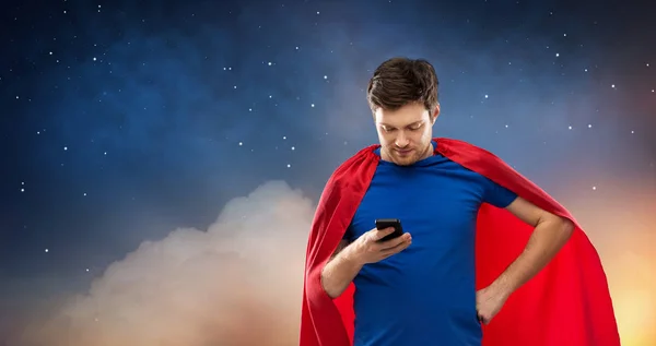 Jeune homme en cape de super-héros rouge en utilisant smartphone — Photo