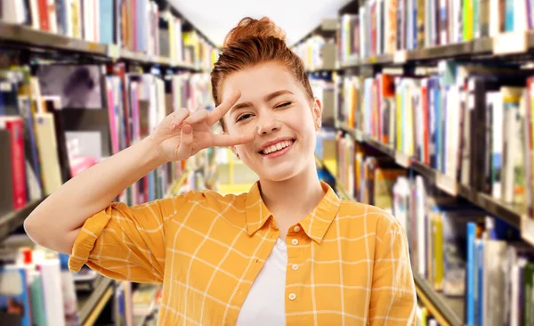 Kütüphanede barış gösteren kırmızı saçlı öğrenci kız — Stok fotoğraf