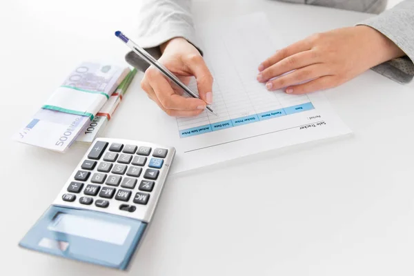 Manos con formulario de impuestos, calculadora y dinero en la mesa — Foto de Stock