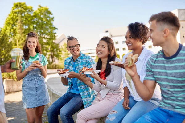 Amigos comiendo sándwiches o hamburguesas en el parque — Foto de Stock