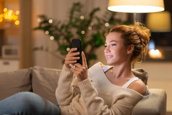 Gelukkig jonge vrouw met smartphone thuis — Stockfoto