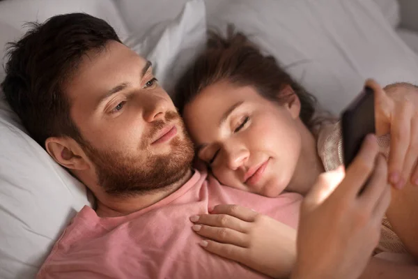 Man met smartphone terwijl vriendin is slapen — Stockfoto