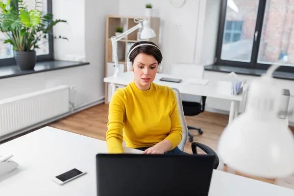 Ofiste kulaklık ve laptop ile iş kadını — Stok fotoğraf