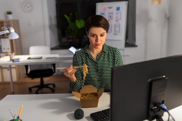 Деловая женщина ест и работает в ночном офисе — стоковое фото