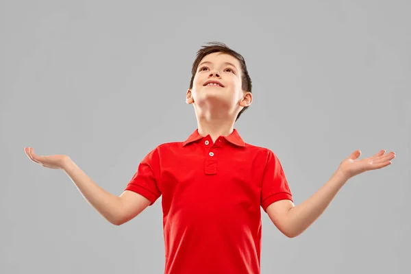 Lycklig tacksam pojke i röd t-shirt tittar upp — Stockfoto