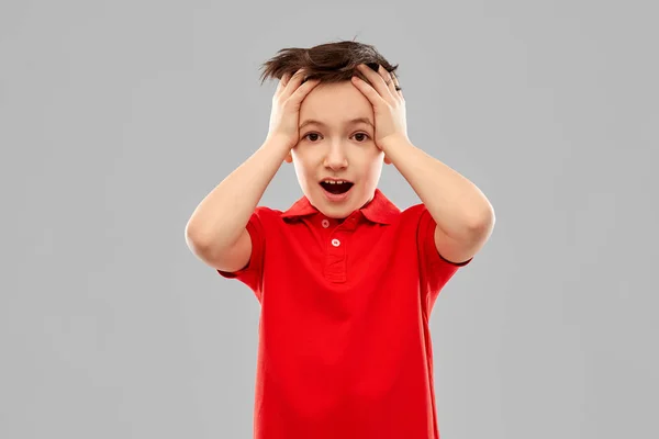 Petit garçon choqué en t-shirt rouge touchant la tête — Photo