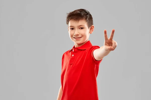 Lachende jongen in rood t-shirt met vrede gebaar — Stockfoto