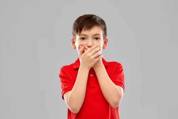 Shocked boy in red t-shirt closing mouth by hands — Stock Photo, Image