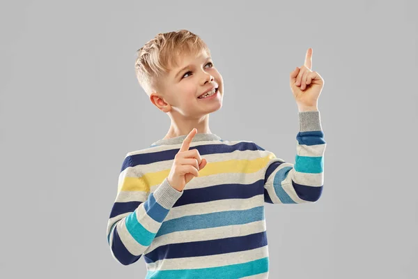 Chlapeček v pruhovaný svetr ukazující prst nahoru — Stock fotografie