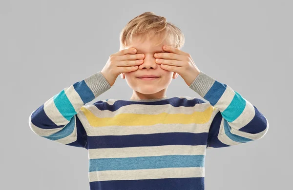 Boy in striped pullover closing his eyes by hands — Stock Photo, Image