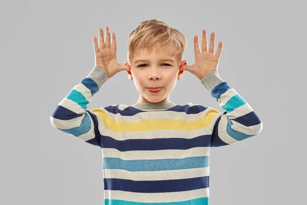 Little boy in red t-shirt making big ears by hands — Stock Photo, Image