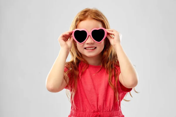 웃는 빨간 머리 소녀에 심장 모양의 선글라스 스톡 사진