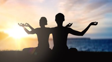 couple doing yoga in lotus pose over sunset clipart