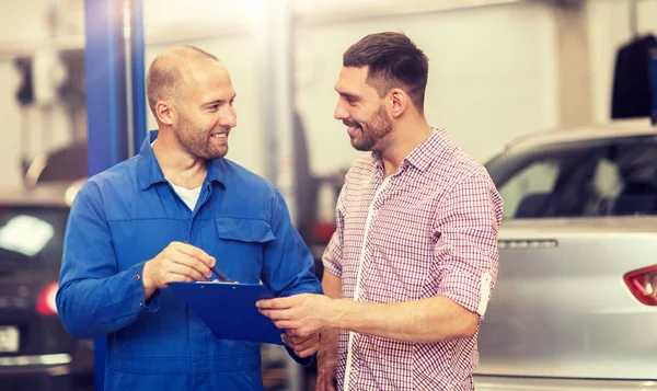 Auto mekaniker med Urklipp och man på bilverkstad — Stockfoto