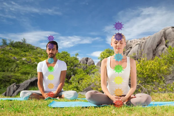 Pareja haciendo yoga en pose de loto con siete chakras —  Fotos de Stock