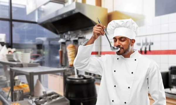 Indian chef tasting food from ladle at kebab shop — Stock Photo, Image