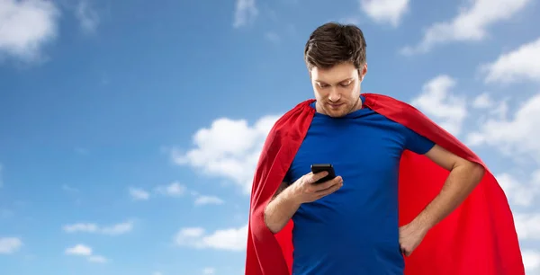 Homme en cape de super héros rouge avec smartphone sur le ciel — Photo