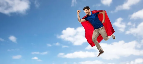 Hombre en capa de superhéroe rojo volando sobre el cielo — Foto de Stock