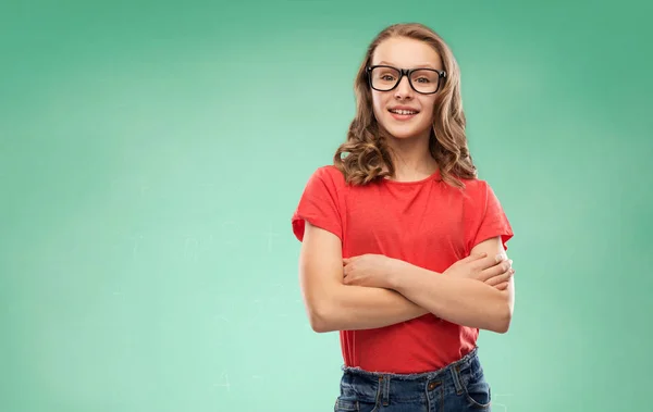 Sorrindo menina estudante em óculos sobre placa verde — Fotografia de Stock