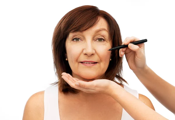 Äldre kvinna och händer med kosmetiska markör — Stockfoto