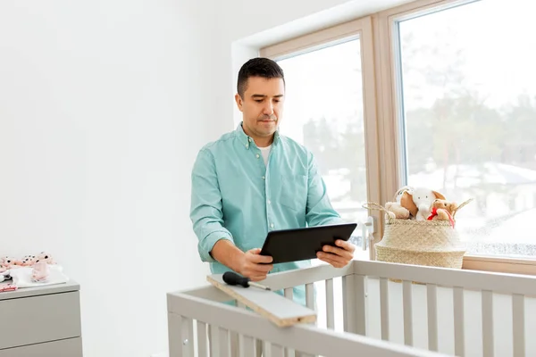 Vader met tablet pc monteren babybed thuis — Stockfoto