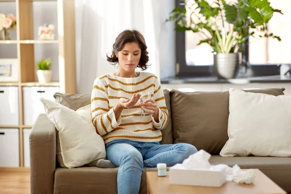 Zieke vrouw die thuis medicijnen met water inneemt — Stockfoto