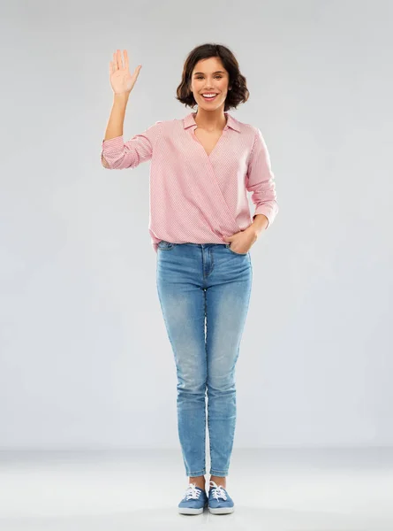 Jovem mulher de camisa e jeans acenando mão — Fotografia de Stock