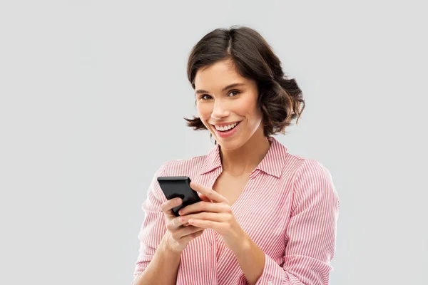Νεαρή γυναίκα σε ριγέ πουκάμισο χρησιμοποιώντας smartphone — Φωτογραφία Αρχείου