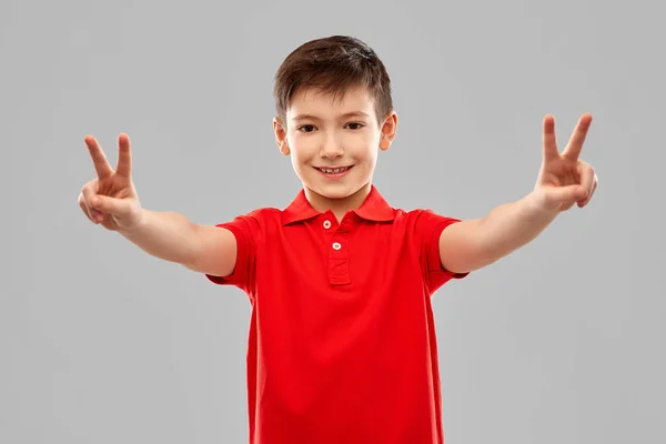 Lachende jongen in rood t-shirt met vrede gebaar — Stockfoto