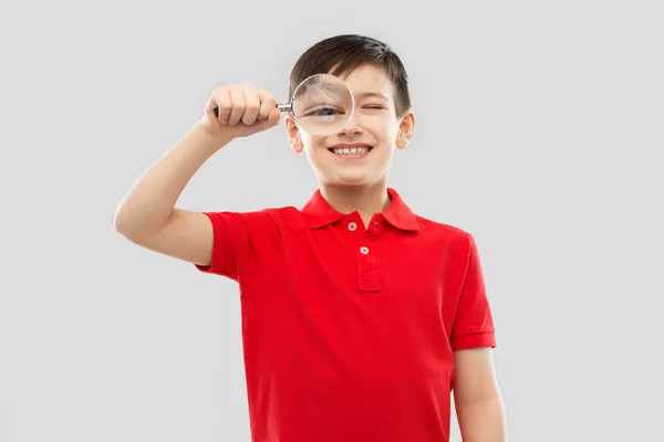 Smiling boy looking through magnifying glass — Stock Photo, Image