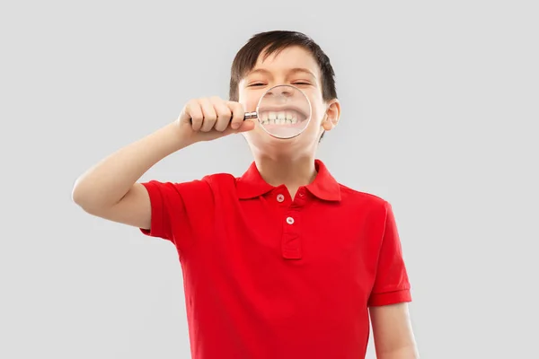 Menino mostrando seus dentes através de lupa — Fotografia de Stock