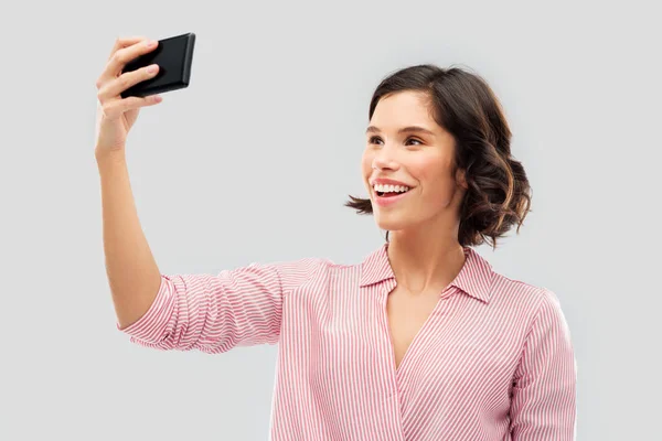 Sonriente joven mujer tomando selfie por teléfono inteligente Fotos de stock libres de derechos