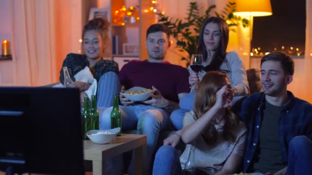 Amigos con bebidas y aperitivos viendo la televisión en casa — Vídeo de stock