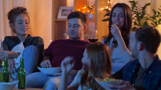 Amigos com bebidas e lanches assistindo tv em casa — Vídeo de Stock