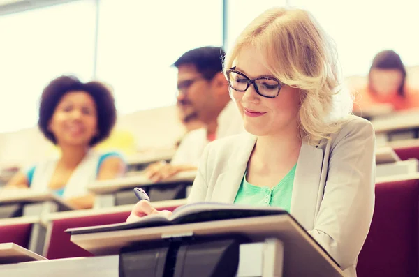 Estudante menina escrevendo para notebook em sala de aula — Fotografia de Stock