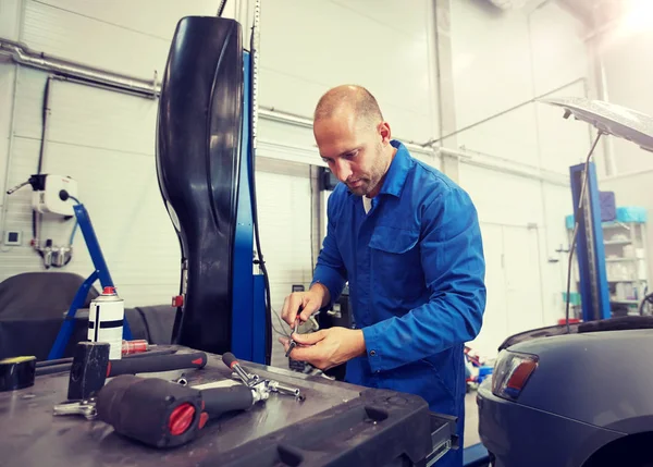 Mechaniker mit Schraubenschlüssel repariert Auto in Werkstatt — Stockfoto