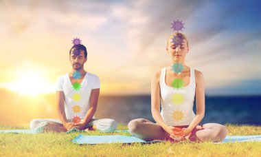 couple doing yoga in lotus pose with seven chakras clipart