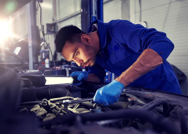 Mecânico homem com lâmpada reparando carro na oficina — Fotografia de Stock