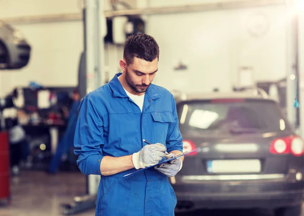 Mecánico de automóviles hombre con portapapeles en taller de coches —  Fotos de Stock