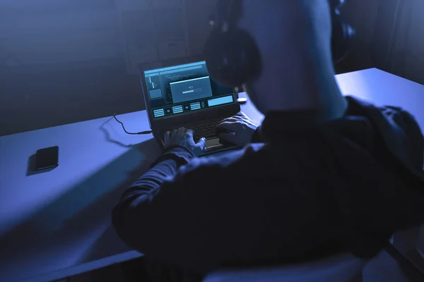 Hacker z paskiem ładowania na laptopie w ciemnym pomieszczeniu — Zdjęcie stockowe