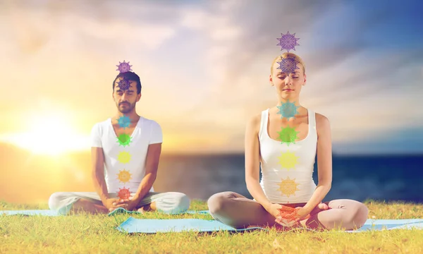 Para uprawia jogę w lotosowej pozie z siedmioma czakrami — Zdjęcie stockowe