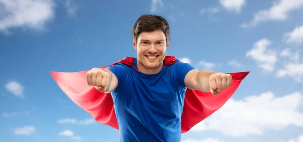 Człowiek w czerwonym Cape superhero nad niebo tle — Zdjęcie stockowe
