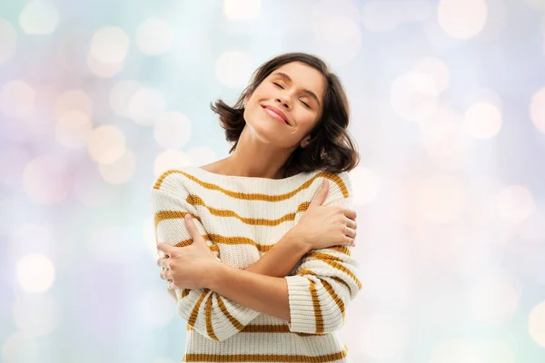 Gelukkige vrouw in gestreepte trui knuffelen zichzelf — Stockfoto