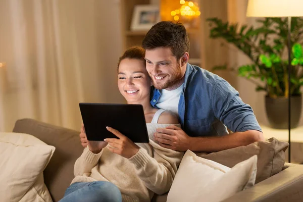 Casal feliz usando tablet pc em casa à noite — Fotografia de Stock